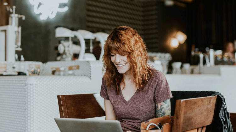 Kvinna vid dator på café